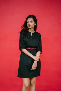 Stüdyo bir güzel, Genç ve çekici Hint Asyalı kadın kırmızı studio çerçevede bir portresi. O zarif bir basit yeşil elbise ve kırmızı kuşak giymiş ve gülüyor.