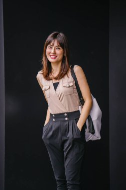 Bir çalışma hanım o pozlar ve onun baş shot siyah bir arka plan için gülümsüyor olarak stüdyo portresi