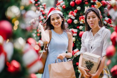 İki genç Asyalı kızlar exchange bir başka gün boyunca şehrin bir sokakta bir şekilde dekore edilmiş bir Noel ağacı altında sunuyor. Hint, diğer Çinli biri