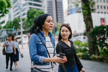 İki arkadaş, Orchard Road, Singapur, Asya 'da aydınlık bir yaz gününde mutlu bir şekilde yürüyüp konuşurlar. Biri Müslüman Malezyalı, diğeri Çinli bir kadın.. 