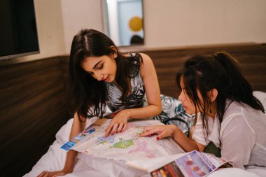 İki genç Asyalı arkadaş bir pansiyonda bir yatakta oturuyor. İkisi de Asyalı ve birlikte seyahat ediyorlar. Biri Hintli, diğeri Çinli. İkisi de gündelik giysiler içinde ve odalarında dinleniyorlar..