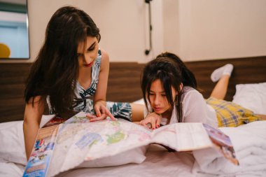 İki genç Asyalı arkadaş bir pansiyonda bir yatakta oturuyor. İkisi de Asyalı ve birlikte seyahat ediyorlar. Biri Hintli, diğeri Çinli. İkisi de gündelik giysiler içinde ve odalarında dinleniyorlar..