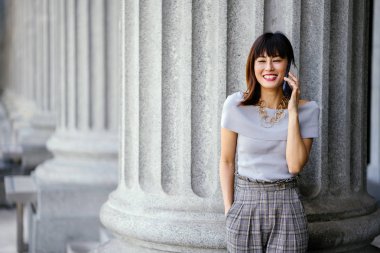 Çekici, kendine güvenen ve başarılı bir Çinli Asyalı kadının portresi. Akıllı telefonunu tutuyor. 