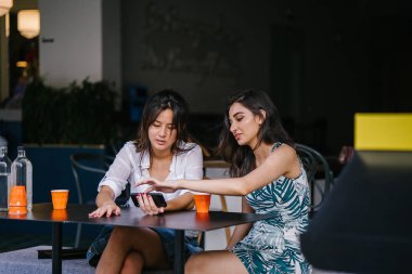 İki yakın arkadaş (kadınlar) gün boyunca bir kafede oturup bir video birlikte Smartphone'da izlerim. Video ve birbirlerinin şirket zevk olarak her ikisi de gülüyorsun.