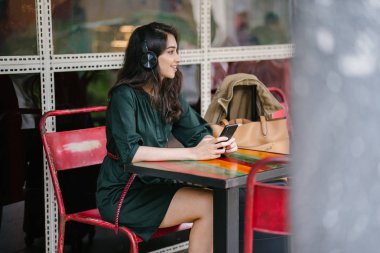 Genç Hintli Asyalı kadın o onun Smartphone-e doğru onun kulaklık streaming müzik hoşlanır