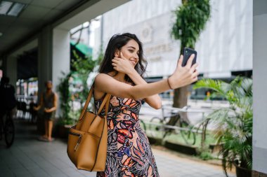 Genç, güzel ve zarif Punjabi Hint Asyalı kadın kendini bir selfie onun smartphone ile yoğun bir cadde üzerinde gün boyunca alır