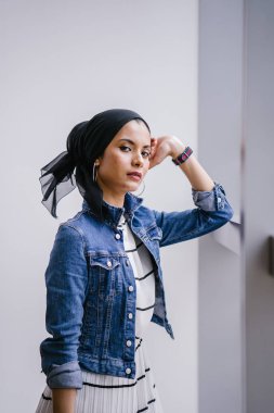 Genç, zarif ve çekici Malezyalı Müslüman kadın gün boyunca elbise ve kot ceket giyiyor..