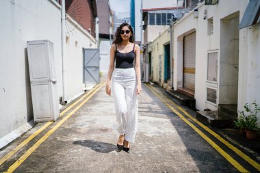 Genç, uzun boylu, ince ve zarif Hint Asyalı kadın rahat bir kıyafet içinde Asya bir sokakta bir sokakta aşağı gün boyunca yürür