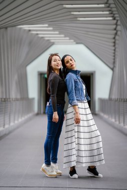 Gündüz vakti köprüde farklı etnik kökenlere sahip iki arkadaş. Biri Malezyalı Müslüman bir kadın, diğeri de Çinli bir Asyalı. İkisi de genç, enerjik ve çekici..