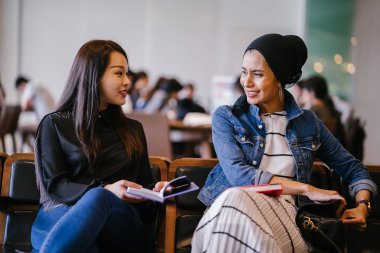 İki genç bayan arkadaş bankta oturup kitap okuyor ve tartışıyorlar. Biri Müslüman Malezyalı, diğeri Çinli bir kadın.. 
