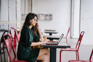 genç üniversite öğrencisi (Hint Asyalı kadın) eğitim ve gün boyunca dizüstü bilgisayar bir masa başında çalışma