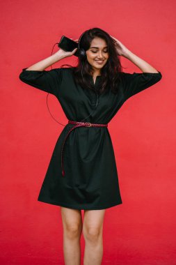 Bir güzel, Genç ve çekici Hint Asyalı kadın bir yeşil elbise ve kırmızı bir arka plan kırmızı kemer Studio portresi