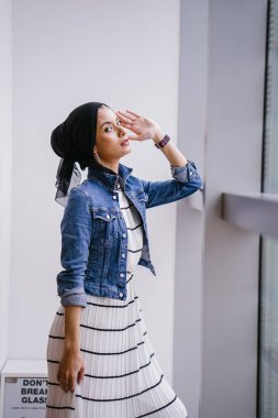 Genç, zarif ve çekici Malezyalı Müslüman kadın gün boyunca elbise ve kot ceket giyiyor..