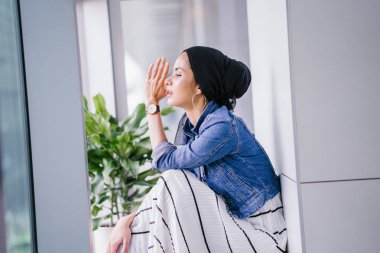 Genç, zarif ve çekici Malezyalı Müslüman kadın gün boyunca elbise ve kot ceket giyiyor..