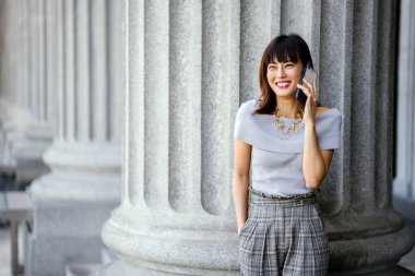 Çekici, kendine güvenen ve başarılı bir Çinli Asyalı kadının portresi. Akıllı telefonunu tutuyor. 