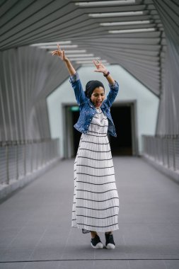 Genç, zarif ve çekici Malezyalı Müslüman kadın gün boyunca elbise ve kot ceket giyiyor..