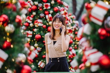 güzel orta yaşlı kadın mutlu onun smartphone üzerinde konuşuyor ve aynı derecede o durgunluk ortasında güzel gülümseyen gün boyunca Noel ağaçları dekore edilmiş olan