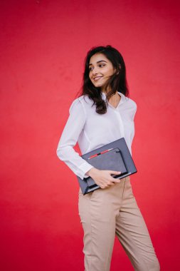 O onun laptop ve defter tutar olarak beyaz bir gömlek ve kahverengi pantolon giyen genç Hintli Asya öğrenci kız portresi.