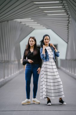 Gündüz vakti köprüde farklı etnik kökenlere sahip iki arkadaş. Biri Malezyalı Müslüman bir kadın, diğeri de Çinli bir Asyalı. İkisi de genç, enerjik ve çekici..