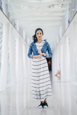 Genç, zarif ve çekici Malezyalı Müslüman kadın gün boyunca elbise ve kot ceket giyiyor..