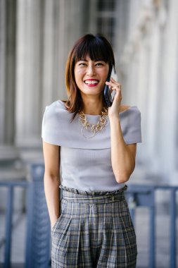 Çekici, kendine güvenen ve başarılı bir Çinli Asyalı kadının portresi. Akıllı telefonuyla konuşuyor. 