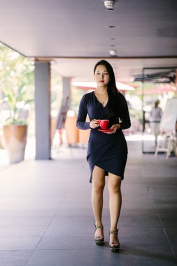 Modern bir altın özelliği duvara karşı şık ve zarif mavi elbise genç ve güzel Asyalı Çinli kadın Portresi. O bir fincan çay tutuyor ve kibirli ve aristokrat görünür. 