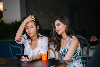 İki yakın arkadaş (kadınlar) gün boyunca bir kafede oturup bir video birlikte Smartphone'da izlerim. Video ve birbirlerinin şirket zevk olarak her ikisi de gülüyorsun.