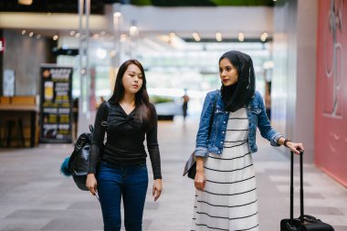 İki arkadaş, Orchard Road, Singapur, Asya 'da aydınlık bir yaz gününde mutlu bir şekilde yürüyüp konuşurlar. Biri Müslüman Malezyalı, diğeri Çinli bir kadın.. 