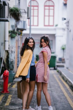 iki yakın arkadaş birlikte bir ara Sokaktan yürürken. Onlar birlikte mutlu bir şekilde yürürken onlar hem trendy retro giyim ve tutuşup giyiyorsun. Çince, diğer Hint biri