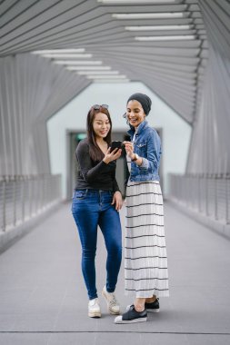 Gündüz vakti köprüde farklı etnik kökenlere sahip iki arkadaş. Biri Malezyalı Müslüman bir kadın, diğeri de Çinli bir Asyalı. İkisi de genç, enerjik ve çekici..