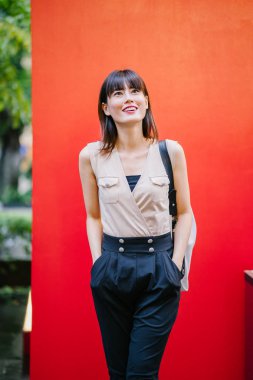 Bir çalışma hanım o pozlar ve onun baş shot kırmızı bir arka plan için gülümsüyor olarak stüdyo portresi