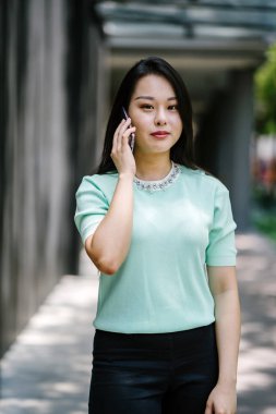 Akıllı telefondan konuşan genç ve güzel Asyalı bir Çinli kadının portresi.