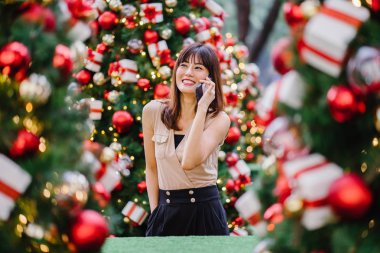 güzel orta yaşlı kadın mutlu onun smartphone üzerinde konuşuyor ve aynı derecede o durgunluk ortasında güzel gülümseyen gün boyunca Noel ağaçları dekore edilmiş olan