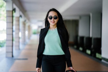 Genç bir Asyalı kadın bavulunu çekiyor. O çekici, zarif ve şık giyinmiş