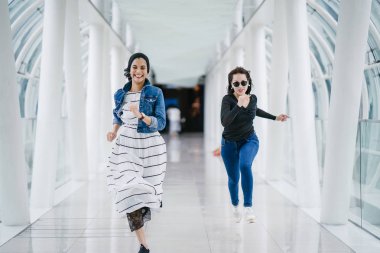 İki farklı arkadaş, iyi aydınlatılmış beyaz fütüristik bir üstgeçit köprüsünden kameraya doğru koşuyorlar. Biri Müslüman bir Orta Doğulu kadın, diğeri de Çinli..