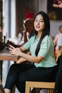 Akıllı telefon tutan genç ve güzel Asyalı bir Çinli kadının portresi.