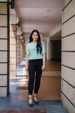 Gündüz vakti genç, seksi ve çekici bir Asyalı kadının portresi. O nane yeşili bir kazak giyiyor.