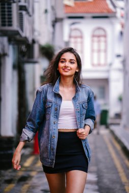 gün boyunca şehrin sokakta yürürken uzun boylu, genç ve zarif Hint Asyalı bir kadın. O bir retro Kot ceket giyiyor