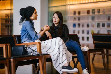 İki bayan arkadaş bankta oturup sohbet ediyorlar. Biri Çinli, diğeri Müslüman.