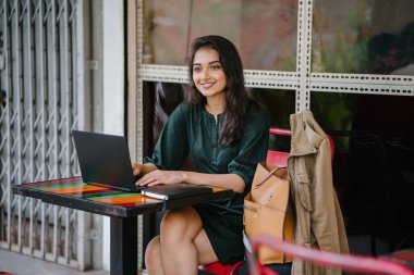 genç üniversite öğrencisi (Hint Asyalı kadın) eğitim ve gün boyunca dizüstü bilgisayar bir masa başında çalışma