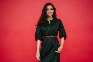 Stüdyo bir güzel, Genç ve çekici Hint Asyalı kadın kırmızı studio çerçevede bir portresi. O zarif bir basit yeşil elbise ve kırmızı kuşak giymiş ve gülüyor.