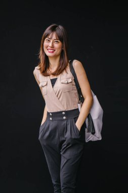 Bir çalışma hanım o pozlar ve onun baş shot siyah bir arka plan için gülümsüyor olarak stüdyo portresi