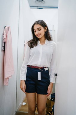 Trying dışarı giyim moda mağaza montaj odasında bir genç, uzun boylu, güzel ve zarif Hint Asyalı kadın portresi.