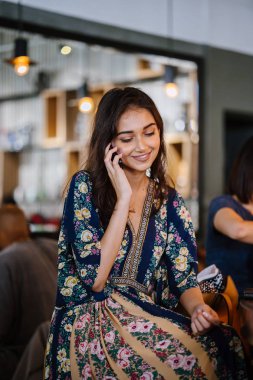 Bir kafede onu smartphone o görüşmeler olarak gündüzleri çatık bir genç ve çekici Hint Asyalı kadın portresi