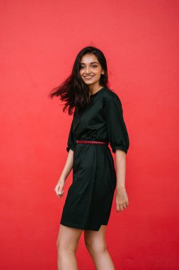 Stüdyo bir güzel, Genç ve çekici Hint Asyalı kadın kırmızı studio çerçevede bir portresi. O zarif bir basit yeşil elbise ve kırmızı kuşak giymiş ve gülüyor.