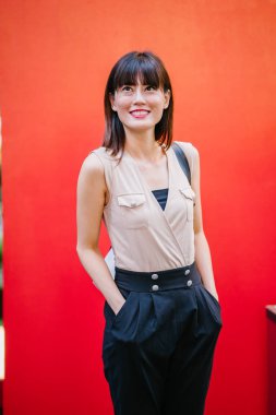 Bir çalışma hanım o pozlar ve onun baş shot kırmızı bir arka plan için gülümsüyor olarak stüdyo portresi