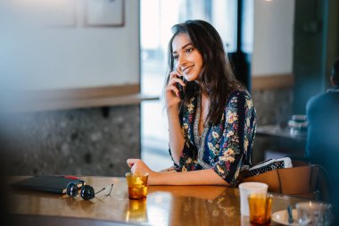 Bir kafede onu smartphone o görüşmeler olarak gündüzleri çatık bir genç ve çekici Hint Asyalı kadın portresi