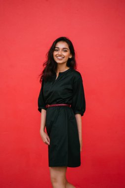 Stüdyo bir güzel, Genç ve çekici Hint Asyalı kadın kırmızı studio çerçevede bir portresi. O zarif bir basit yeşil elbise ve kırmızı kuşak giymiş ve gülüyor.