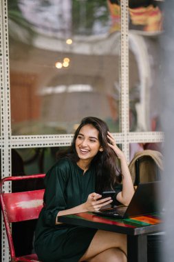 Genç Singpaorean Kızılderili kadın eğitim ya da bir kafede gün boyunca onu laptop çalışan bir mola alır gibi onun smartphone kontrol