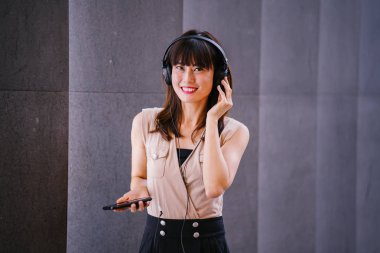 Onun kulaklık müzik dinlemek orta yaşlı, fotojenik bir Çinli kadın portresi